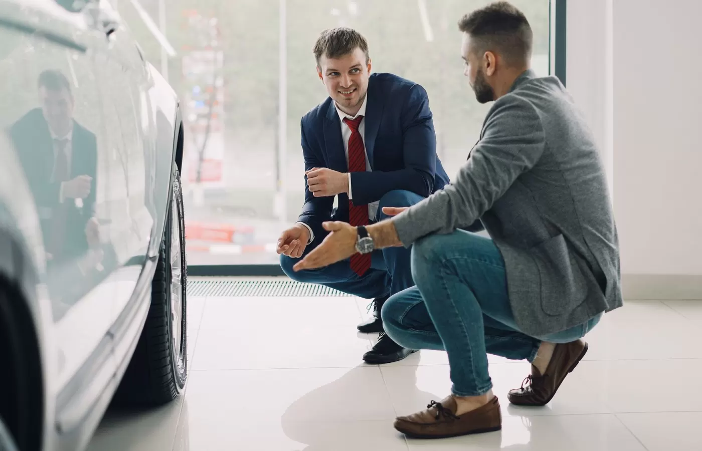A salesperson walking a customer around a new vehicle
